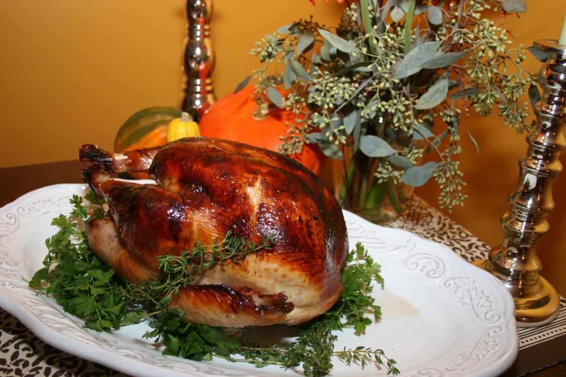 roast turkey on a platter garnished with fresh herbs